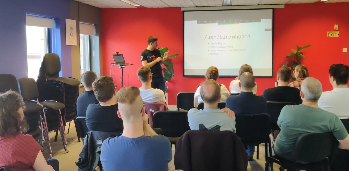 A photo of the DevOpsNotts meetup, with Jamie at the front presenting a slide titled /usr/bin/whoami